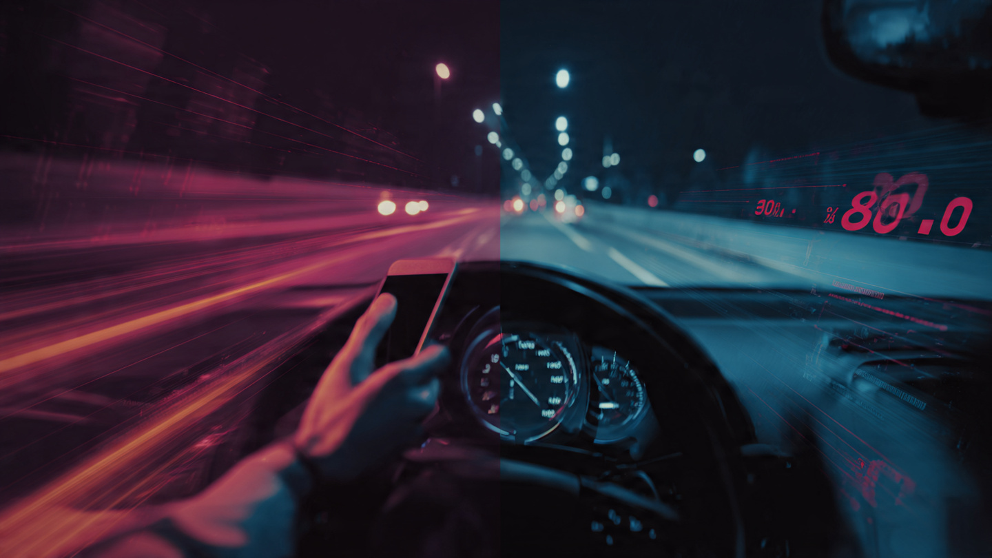 A nighttime highway scene showing a driver's hand holding a glowing smartphone over the steering wheel with a speedometer pushing past 80mph